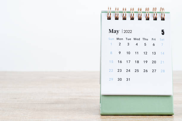 May 2022 desk calendar on wooden background.
