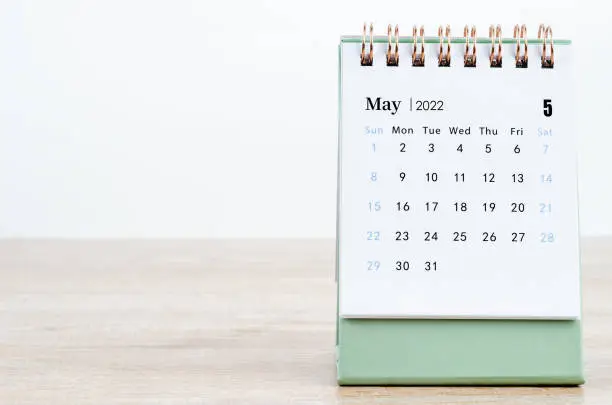 Photo of May 2022 desk calendar on wooden background.