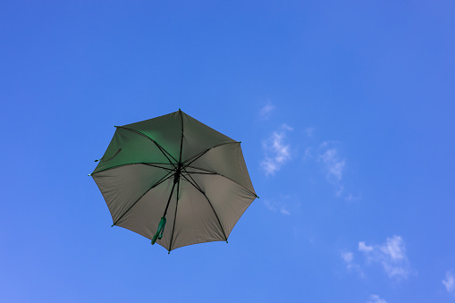 A close-up view from the low, a beautiful opaque bronze umbrella floating freely in the blue sky in the springtime sunlight of the Thai countryside.