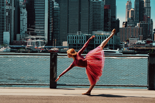 young gorgeous ballerina dancing on street, downtown Brooklyn, New York City financial district cityscape