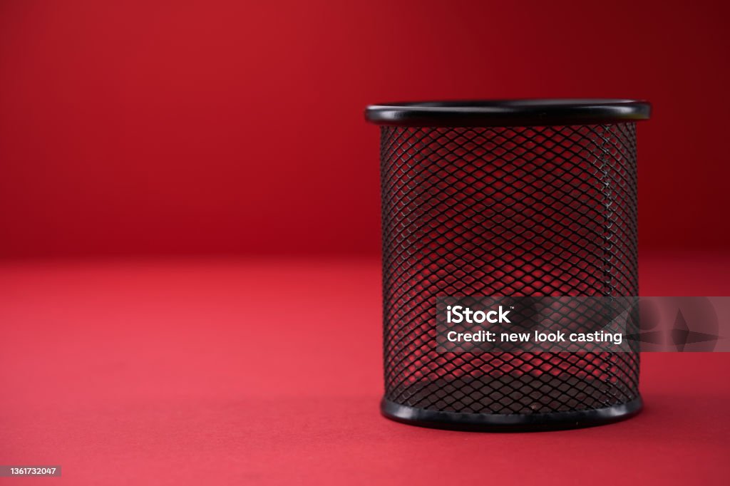 wire trash can on red background Garbage Can Stock Photo