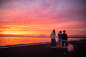 日没時に湘南ビーチから富士山を眺める3人の背面図