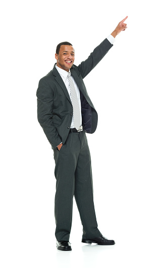 Front view of aged 20-29 years old african-american ethnicity young male presenter standing in front of white background wearing businesswear who is cheerful who is showing with hand