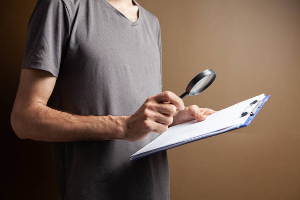 istock a man with a magnifying glass looks at papers 1361738026