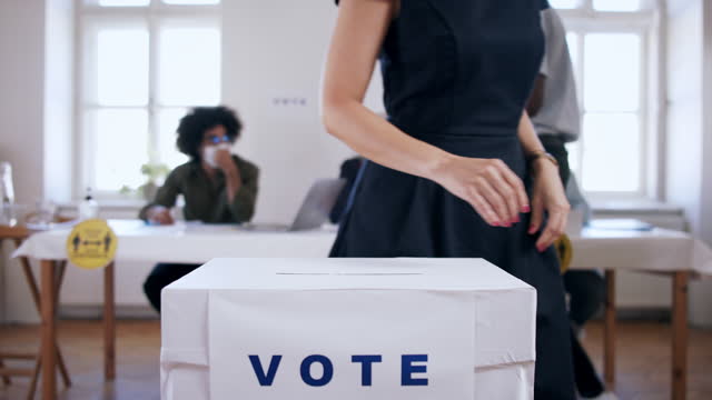 Unrecognizable woman putting her vote in the ballot box, usa elections and coronavirus.