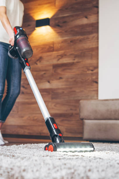 oman cleaning floor and carpet with cordless vacuum cleaner at home. stock photo