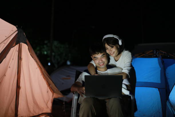 istock Lovely young couple remote working on night at camping site 1361743214