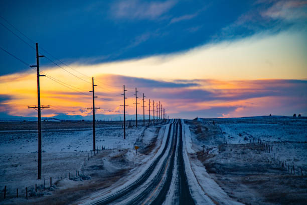 carretera cubierta de nieve de 2 carriles a través de las colinas de montana al atardecer - poste telegráfico fotografías e imágenes de stock