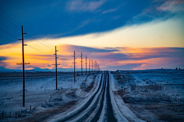 Snow covered 2 lane highway through hills of Montana at sunset Snow covered highway lined with telephone poles through hills of Montana at sunset. This is central Montana in northwestern United States of America. telephone pole stock pictures, royalty-free photos & images