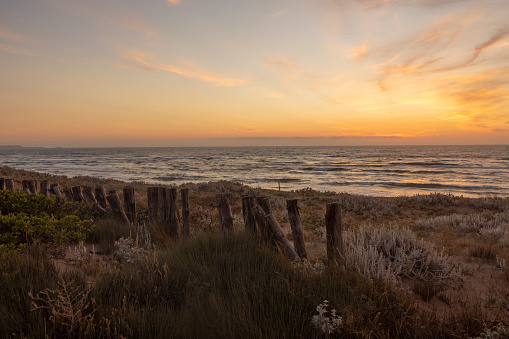 View of a wooden fence along the beach at sunset, Sardinia, Italy.