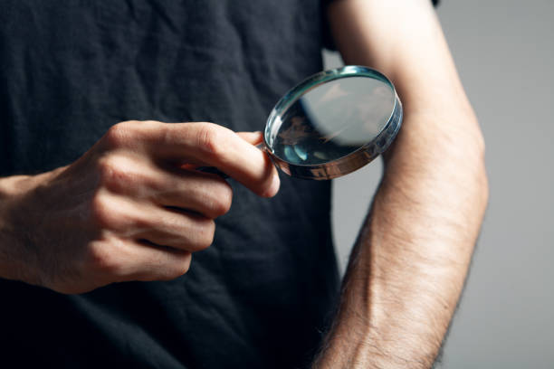 istock a man examines a hand with a magnifying glass 1361747703