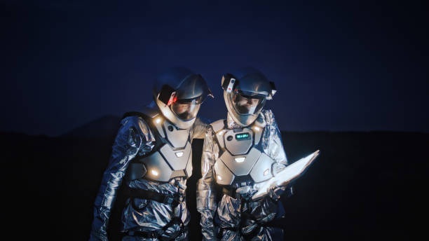 istock Astronauts in futuristic suits looking for a route on new planet with illuminated tablet 1361753761