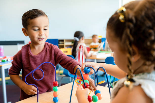 istock Two preschool age children cooperate on bead puzzle 1361756768
