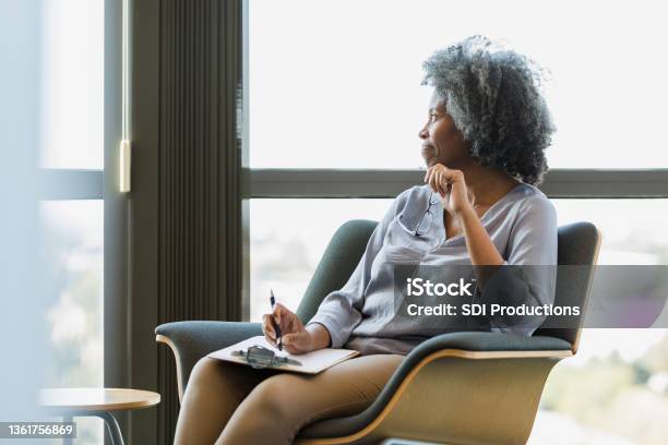 Mature Female Therapist Takes Break In Office To Daydream Stock Photo - Download Image Now