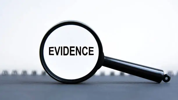 looking through a magnifying glass at the word Evidence, a business concept. magnifying glass on the white background