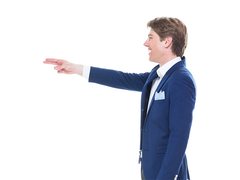 Side view of aged 20-29 years old caucasian young male in front of white background wearing blazer who is happy who is pointing