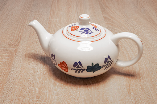 Classic Dutch teapot with a hand-painted farmer's pattern ('boerenbont') on a wooden table.