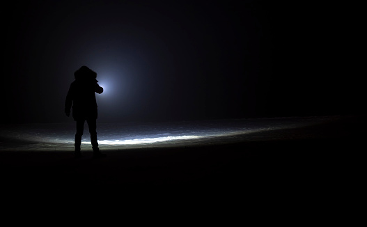 man with flashlight in winter night