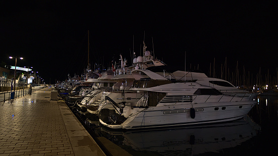 Cannes, Provence-Alpes-Cote d'Azur, France - 11-03-2021: Night view of luxury yacht boats in a row docking at marina Vieux Port de Cannes at the French Riviera with illuminated promenade.