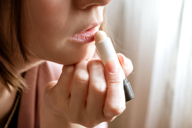 istock Young woman using moisturizing lipbalm, close up 1361765798