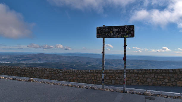 View of signpost on the peak of popular Mont Ventoux ("windy mountain"), Provence, France with stone wall and panoramic view. Mont Ventoux, Provence-Alpes-Cote d'Azur, France - 11-01-2021: View of signpost on the peak of popular Mont Ventoux ("windy mountain"), Provence, France with stone wall and panoramic view. mistral wind stock pictures, royalty-free photos & images