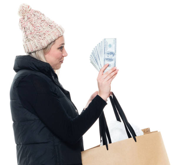 mujer shopaholic delante de fondo blanco usando chaleco y sosteniendo la moneda - laughing women us paper currency isolated fotografías e imágenes de stock