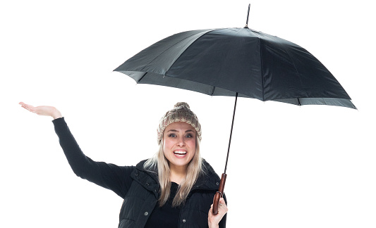 Front view of aged 20-29 years old who is beautiful caucasian young women presenter in front of white background wearing knit hat who is showing with hand presenting and holding umbrella