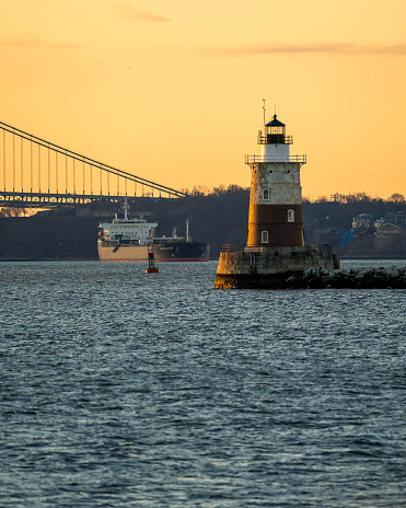 Bayonne, NJ - USA - Dec. 26, 2021: Vertical view at sunrise of the Robbins Reef Lighthouse, a sparkplug lighthouse located off Constable Hook in Bayonne, located near the Kill Van Kull, a tidal strait