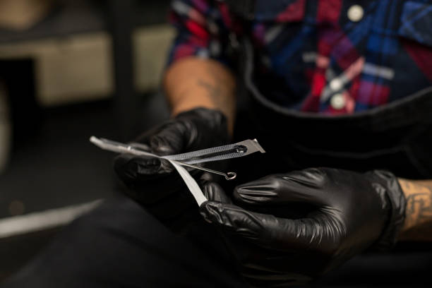 istock Tattoo artist's hands removing the sterilized tattoo needle from its container. He is wearing black gloves. Body art concept 1361766729