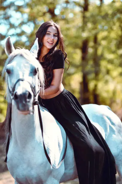 Photo of Smiling Gypsy Female Sitting On Saddleless Horse In Forest