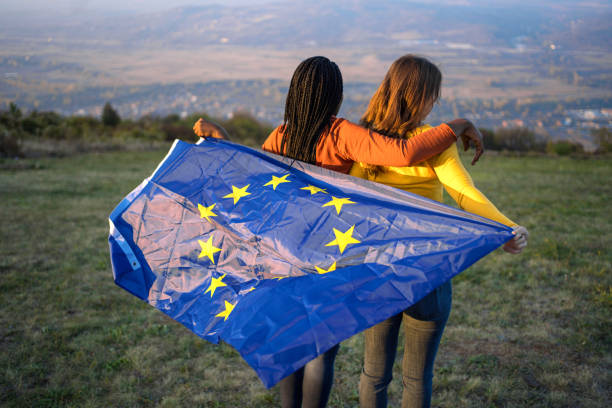 istock Two women standing on hill holding EU flag behind back 1361770638