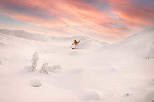 bela vista do esquiador freeride habilmente cavalga pela encosta da montanha contra o céu colorido ao fundo. - freeride - fotografias e filmes do acervo