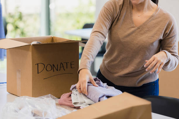 istock Unrecognizable woman sorts donated clothes into box 1361776918