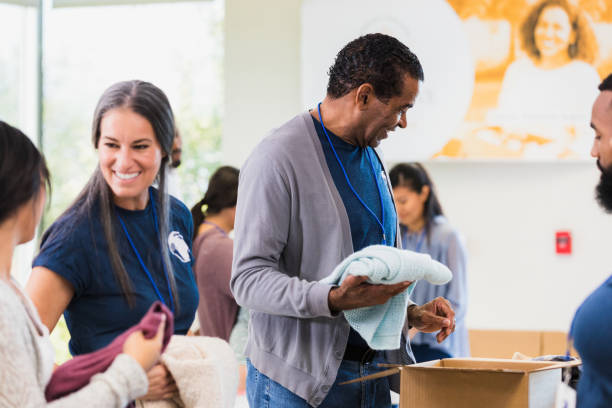istock Diverse volunteers bond while sorting and folding clothing donations 1361778531