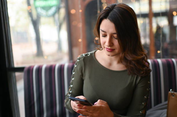 istock Young beautiful woman is using a mobile phone in a coffee bar 1361779029
