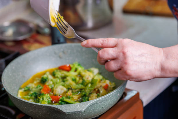 istock female hands adds a scrambled egg yolks to frying vegetables while cooking omelette 1361780356
