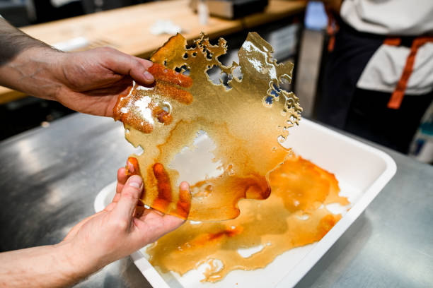 schöne transparente süße goldene geronnene karamellzuckerkruste in männlichen händen - burnt sugar stock-fotos und bilder