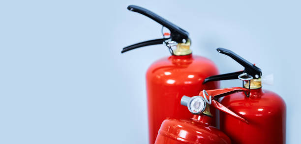 Three red fire extinguishers on a blue background stock photo