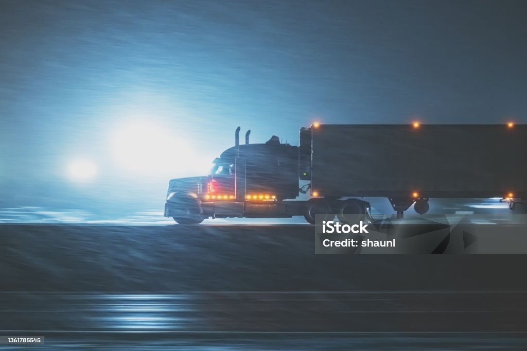Semi Truck on Highway in Winter Semi truck on a multi lane highway during heavy snowfall at night. Photographed at high iso with slight motion blur in some points of the frame. Semi-Truck Stock Photo
