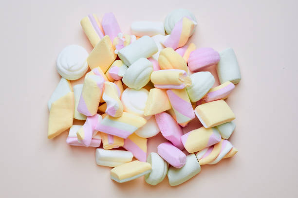pastel colored marshmallows on a pink background stock photo