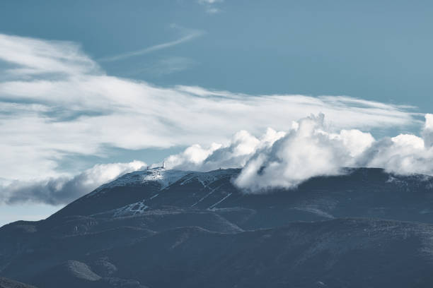 Piegon, France - December 25, 2021. View of a Provence landscape. The summit of Mont Ventoux licked by winter clouds is visible. The towers and astrology observatories installed at the top are visible.