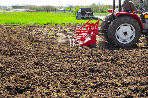 Un tractor ara la tierra en una parcela de jardín en un día de primavera. Agricultura y Agronomía photo