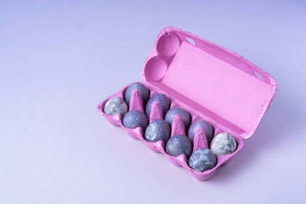 Purple egg packaging with eggs on blue background. Festive Easter concert. Place for text.