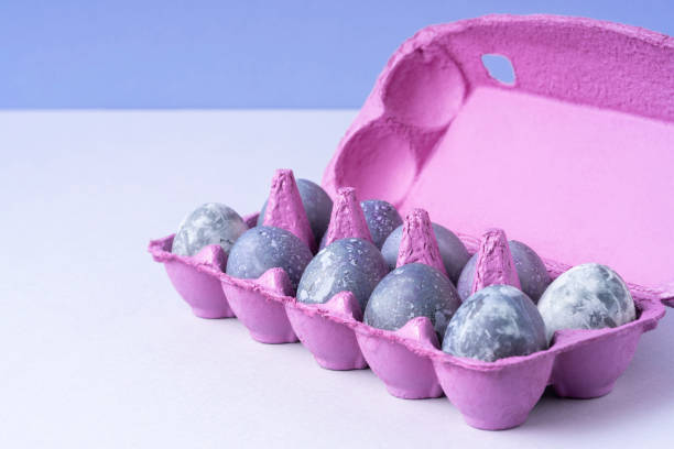 Purple egg packaging with eggs on blue background. Festive Easter concert. Place for text.