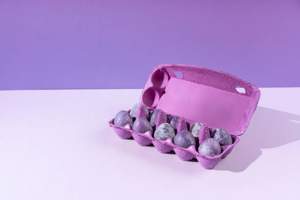 Purple egg packaging with eggs on blue background. Festive Easter concert with hard shadows. Place for text.