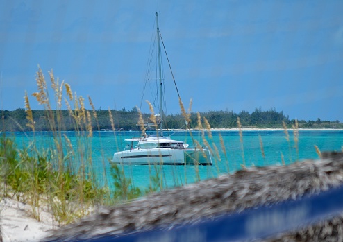 Catamaran moored near the coast in Teasure Cay, Abaco, Bahamas. The people are swimming, diving and chiling on a beautiful sunny day