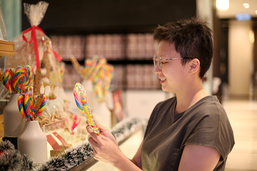 An Asian woman is choosing candy sticks for Christmas celebration in Malaysia.