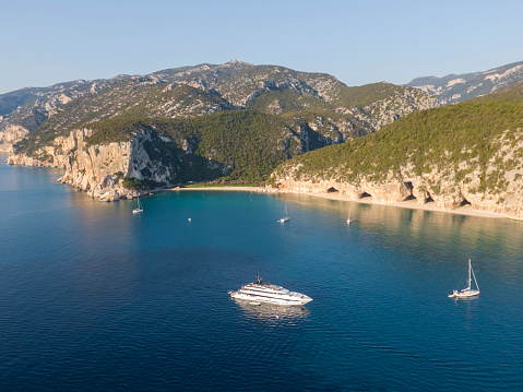 View of a few luxury sailboats near the coastline at Cala Luna caves, Sardinia, Italy.