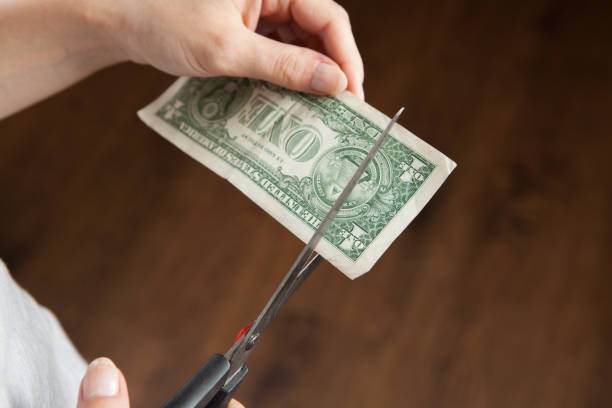 istock woman cuts a dollar bill with scissors 1361805269