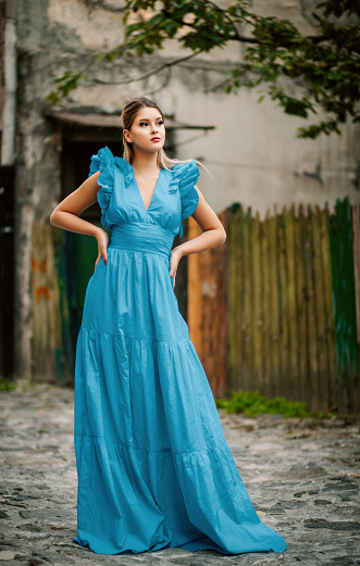 Beautiful young woman walking and exploring old city and wearing blue long dress